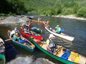 A group of people in canoes on a river Description automatically generated with medium confidence