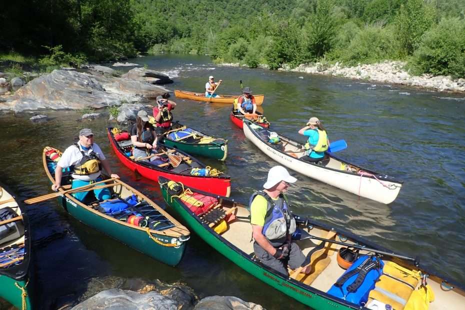A group of people in canoes on a river Description automatically generated with medium confidence