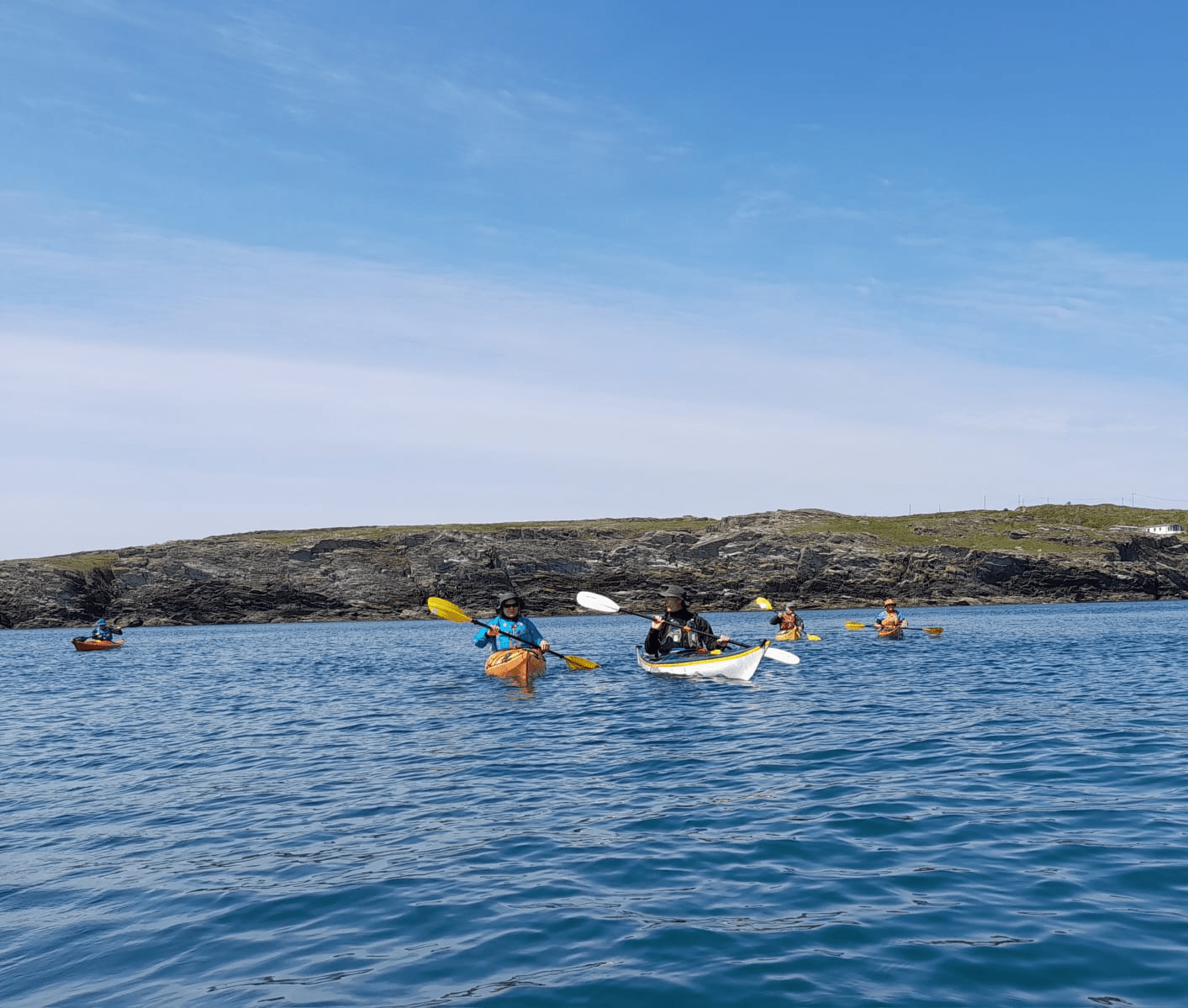 A group of people in kayaks on a body of waterDescription automatically generated
