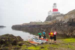 A group of people standing next to kayaks Description automatically generated with medium confidence
