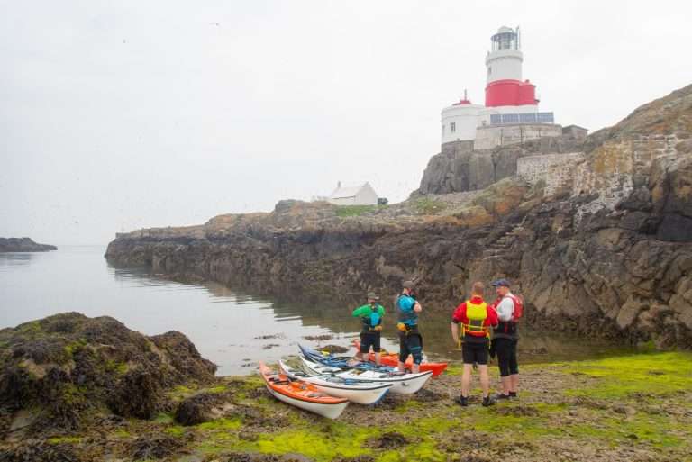A group of people standing next to kayaks Description automatically generated with medium confidence