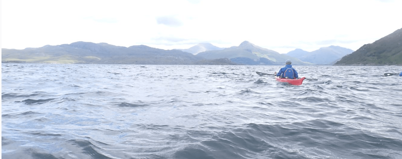 A person on a kayak in the waterDescription automatically generated