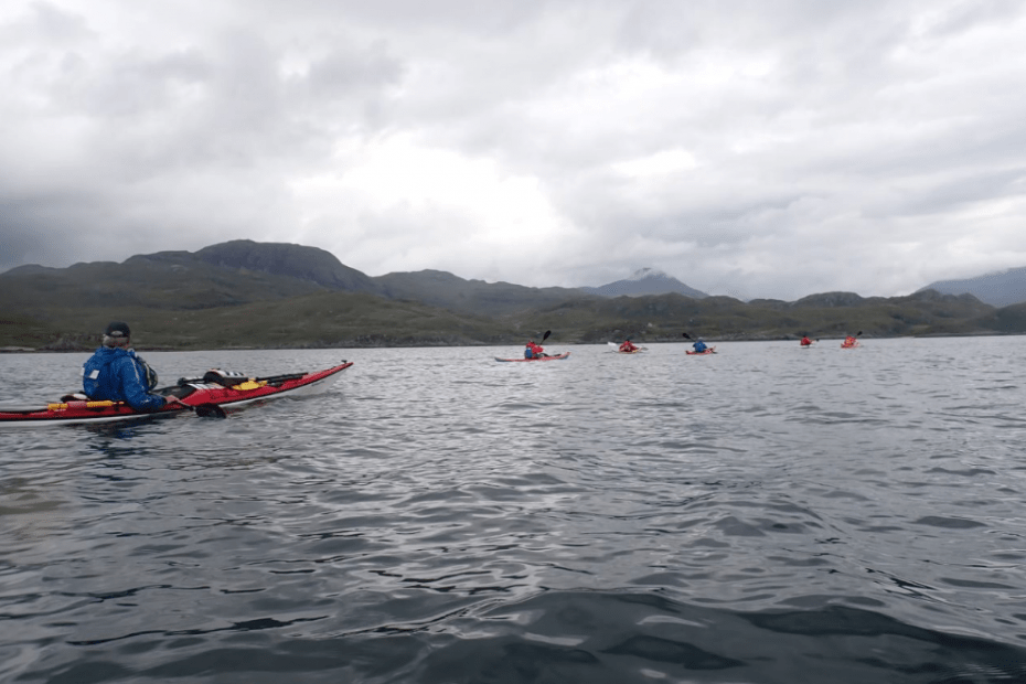 A group of people kayaking in a lake Description automatically generated
