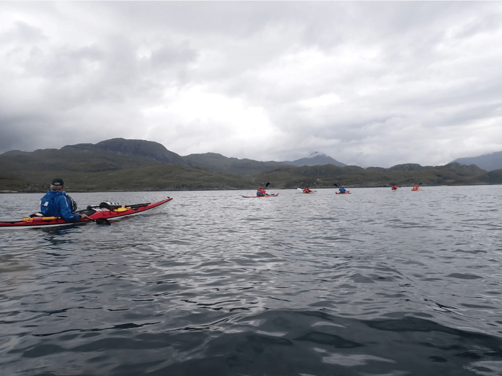 A group of people kayaking in a lakeDescription automatically generated