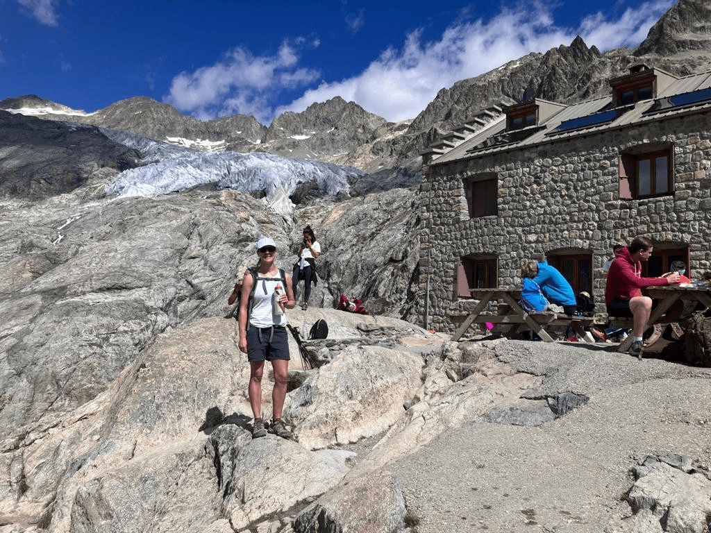 A group of people standing on a rock near a buildingDescription automatically generated