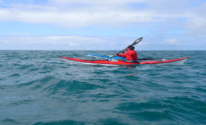 A person in a kayak on the water Description automatically generated