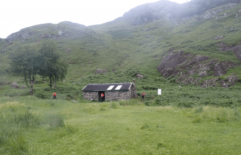 A stone building in a grassy area Description automatically generated