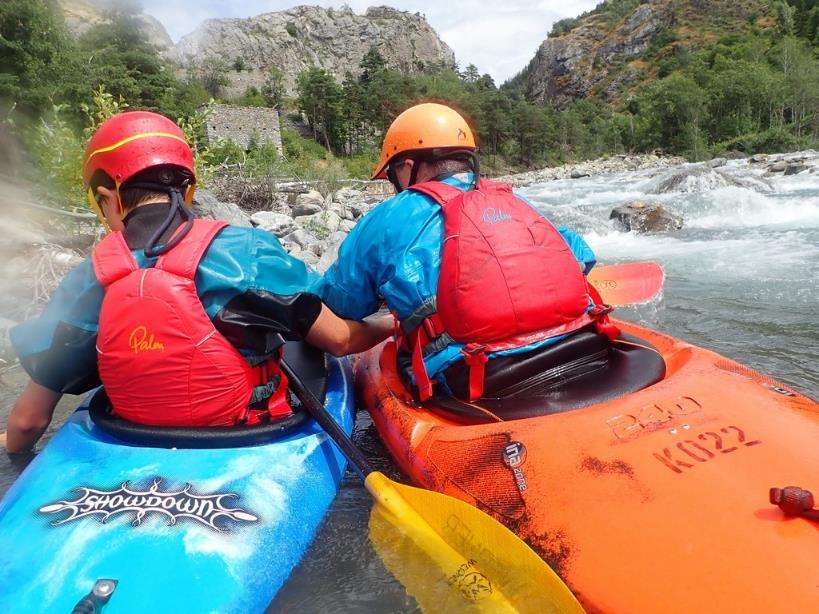 Two people in kayaks in a riverDescription automatically generated