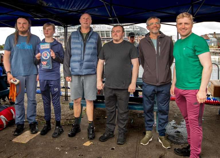 A group of men standing under a blue tent Description automatically generated