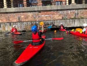 A group of people in kayaks in a river Description automatically generated