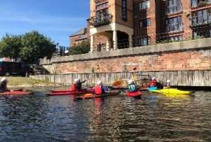 A group of people in kayaks on a river Description automatically generated