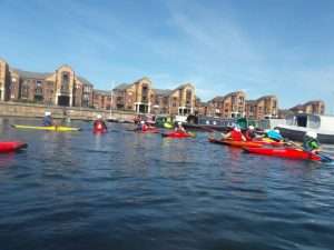 A group of people in kayaks on a river Description automatically generated