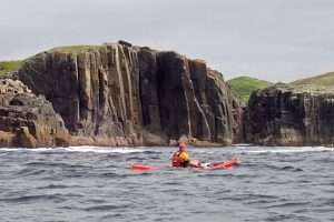 A person in a kayak in the ocean Description automatically generated