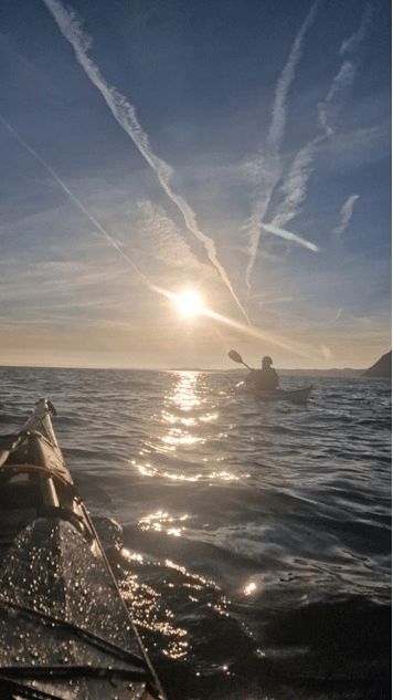 A person in a kayak on the waterDescription automatically generated