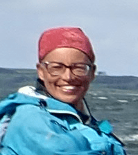 A person wearing glasses and a blue jacketDescription automatically generated