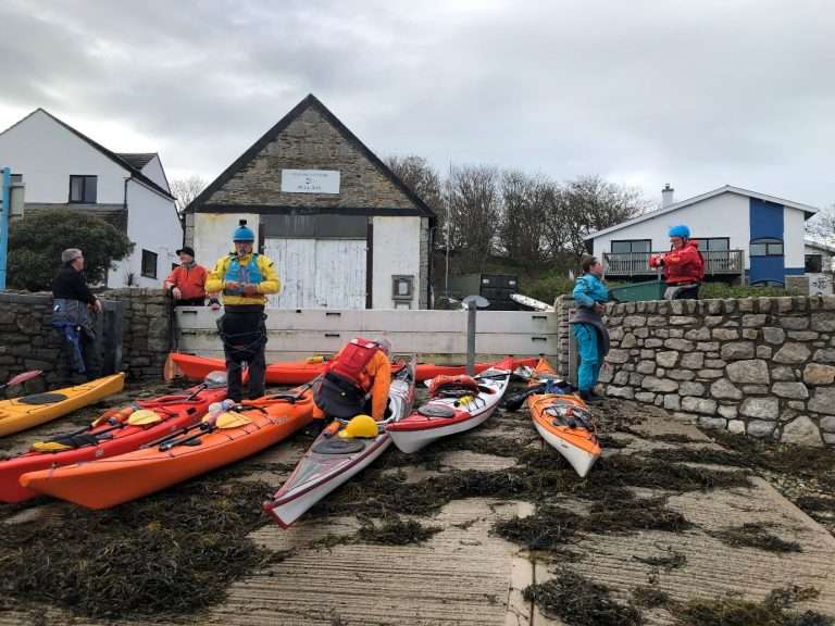 A group of people standing next to kayaks Description automatically generated