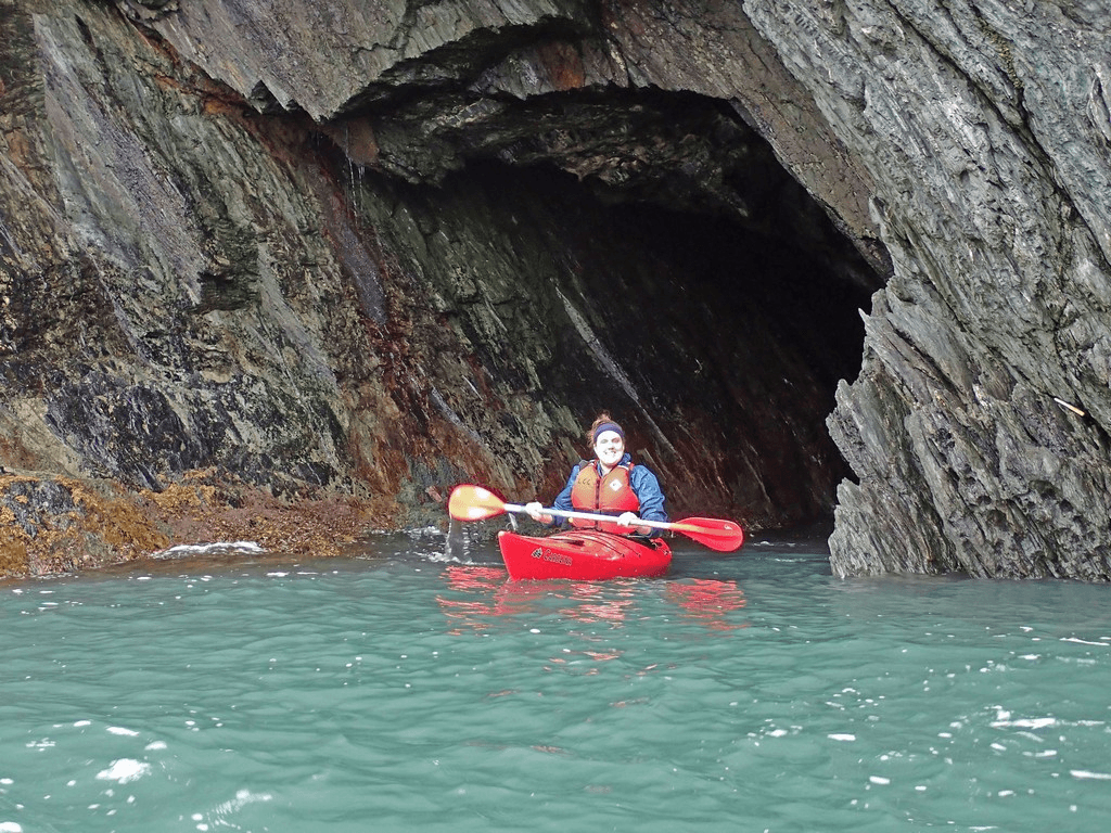 A person in a kayak in a caveDescription automatically generated
