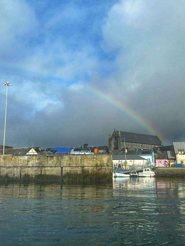 A rainbow over a body of waterDescription automatically generated
