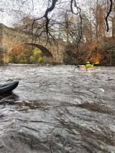 A person in a kayak in a river Description automatically generated
