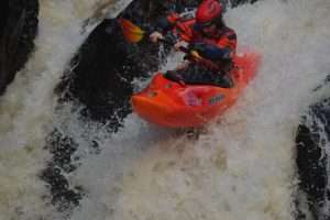 A person in a kayak in a river Description automatically generated