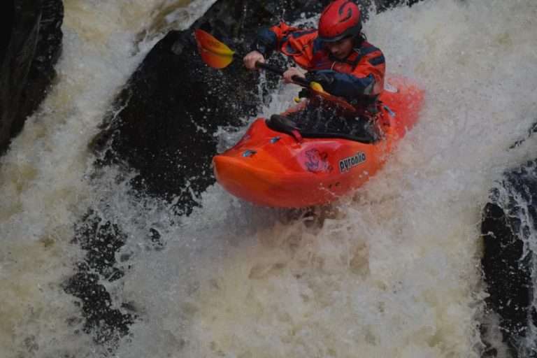 A person in a kayak in a river Description automatically generated