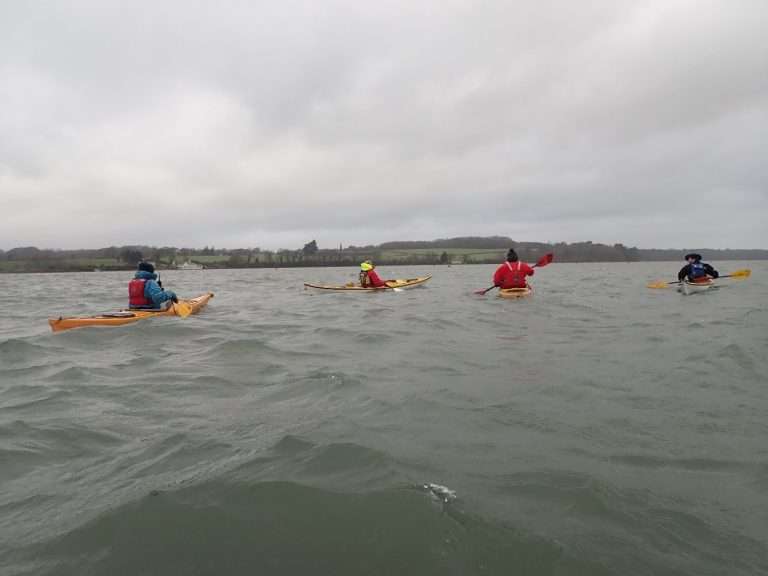 A group of people in kayaks in the water Description automatically generated