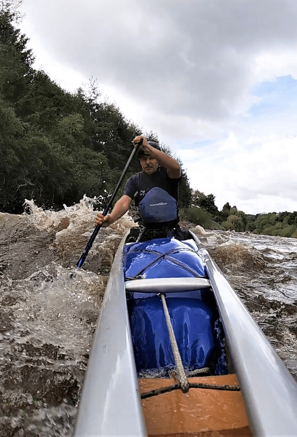 A person in a canoe on a riverDescription automatically generated