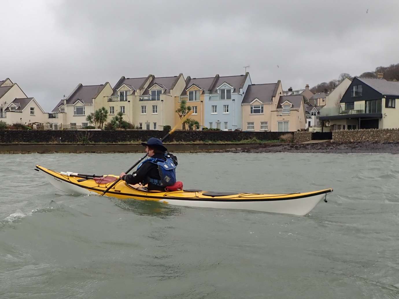 A person in a kayak on the waterDescription automatically generated