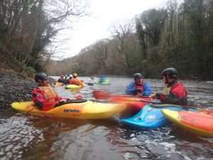 A group of people in kayaks in a river Description automatically generated