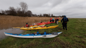 A group of people in kayaks on a river Description automatically generated