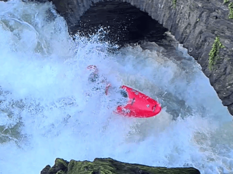 A person in a kayak in a river Description automatically generated
