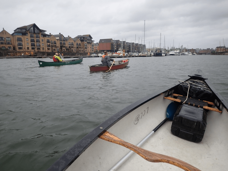 A group of people in boats on a river Description automatically generated