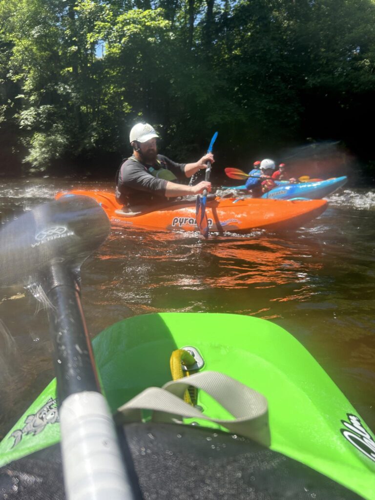 A group of people in kayaks on a river Description automatically generated