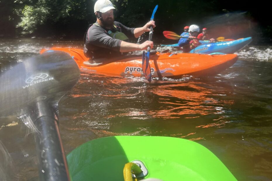 A group of people in kayaks on a river Description automatically generated
