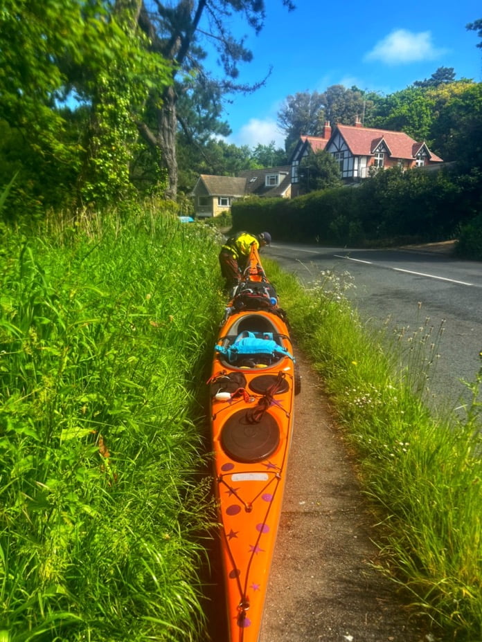 A kayak on a path by a roadDescription automatically generated