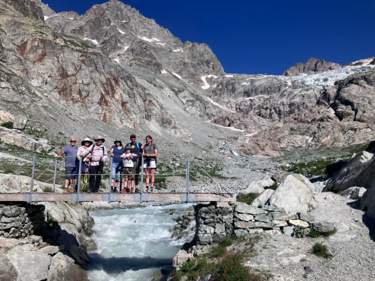 A group of people standing on a bridge over a river Description automatically generated