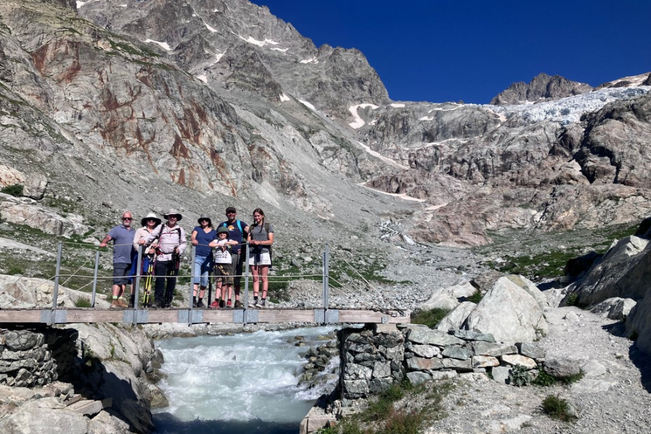 A group of people standing on a bridge over a river Description automatically generated