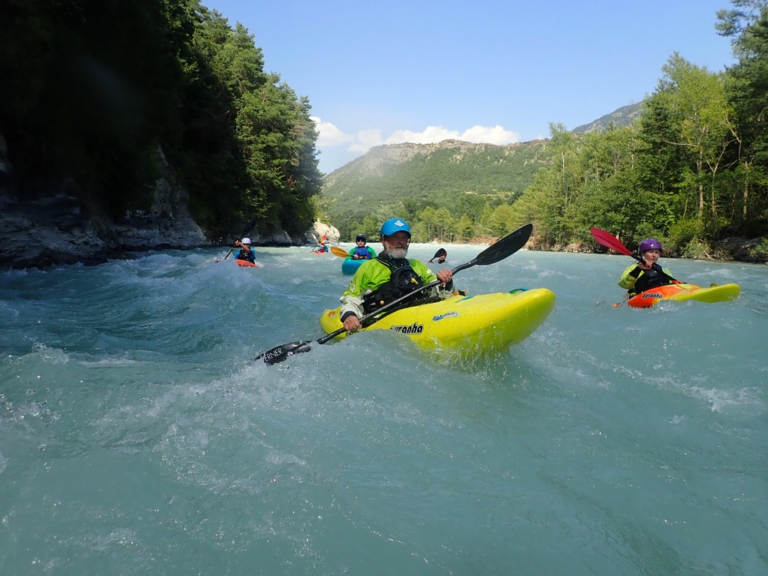 A group of people in kayaks in a river Description automatically generated