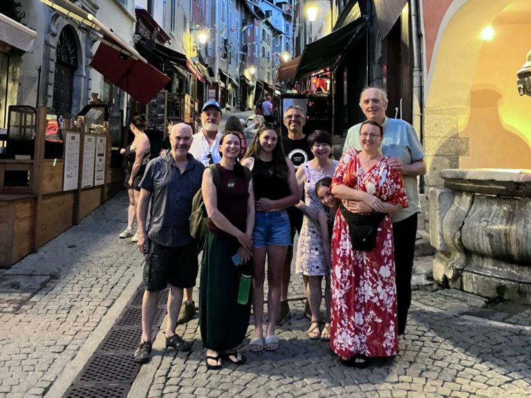 A group of people standing on a cobblestone street Description automatically generated