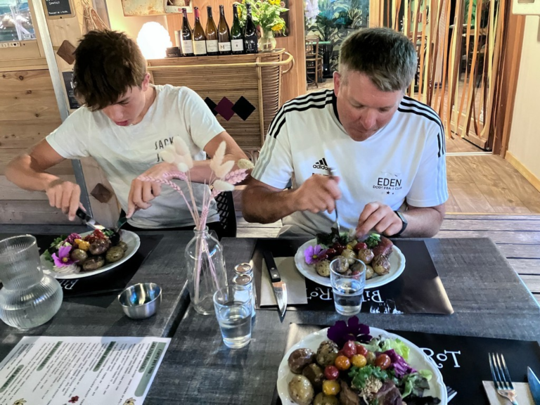 A person and child eating at a table Description automatically generated