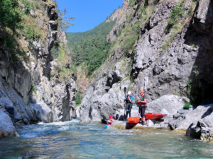 People kayaking in a canyon Description automatically generated