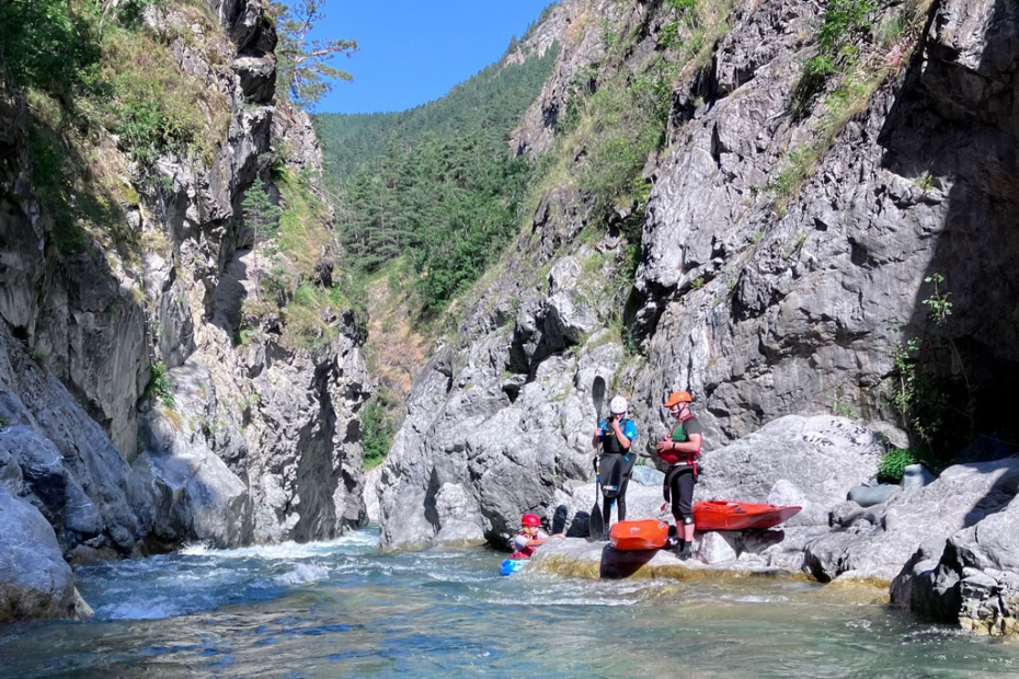 People kayaking in a canyon Description automatically generated