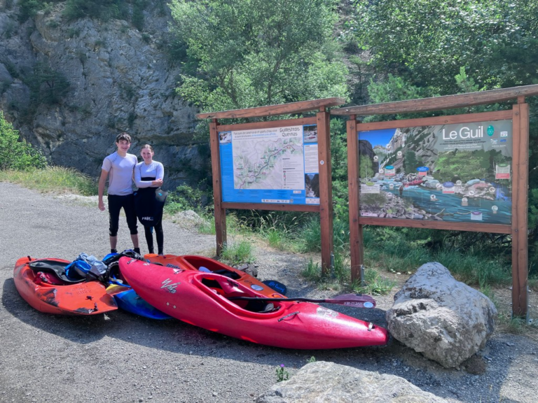 Two people standing next to a sign Description automatically generated