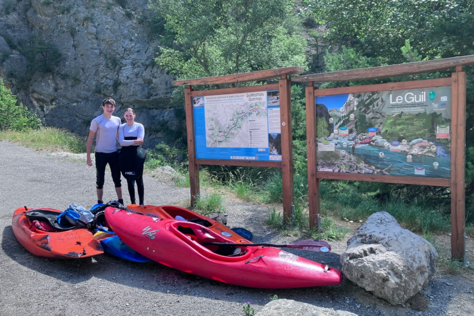 Two people standing next to a sign Description automatically generated