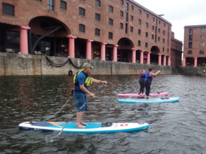 A group of people on paddle boards in water Description automatically generated