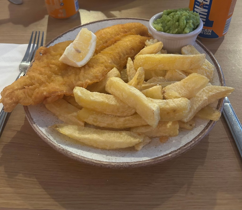 A plate of food with a lemon wedge and friesDescription automatically generated