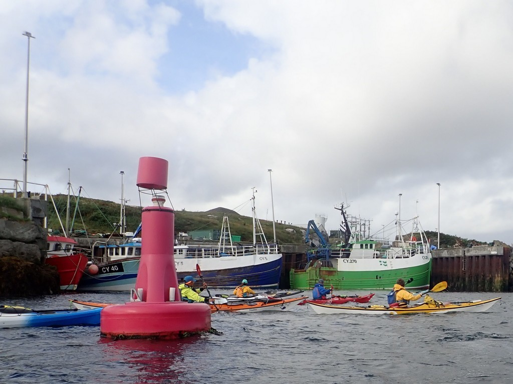 Boats in the water with boats and a buoyDescription automatically generated