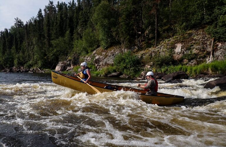 A couple of people in a canoe on a river Description automatically generated