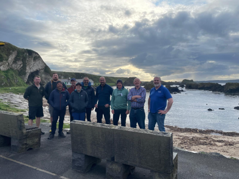 A group of people standing in front of a body of water Description automatically generated