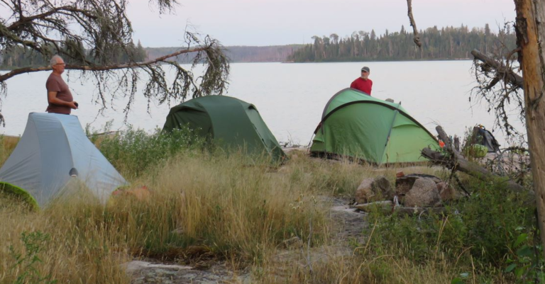 Two tents next to a lake Description automatically generated